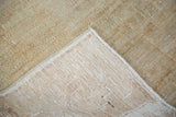 Distressed beige Oushak carpet corner revealing hand-knotted pile and foundation weave.