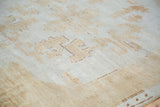 Textured pile of distressed Oushak, showing faded light brown tribal motifs.