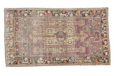 Distressed Oushak runner with geometric medallion, arrows, and multi-color border on faded mauve.