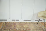 Geometric Turkish Oushak runner with distressed mauve field and faded ornate medallion.
