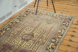 Distressed Oushak runner's corner, featuring intricate geometric border and soft mauve field.