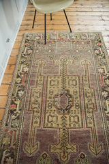 Distressed Oushak runner close-up: geometric medallion, mauve field with saffron, red, and gold.