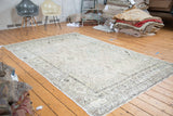 Distressed Oushak carpet featuring faded ivory and stylized geometric patterns.