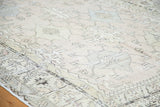 Muted ivory, silver, and blue geometric stylized weaving on a distressed Oushak carpet.