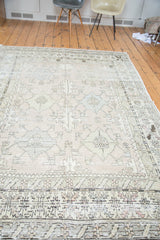 Distressed Oushak carpet detail, geometric stylized weaving in muted ivory, blue, green.