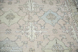 Muted celadon, powder blue, and ivory geometric patterns on a distressed Oushak carpet.