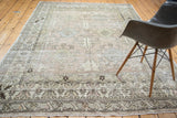 Distressed Turkish Oushak carpet with muted geometric patterns in charcoal, blue, green, and ivory.