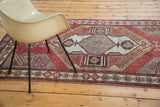 Distressed Oushak runner's tribal geometric latch pattern with brick red, grey, and gold tones.