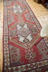 Distressed Oushak runner with tribal geometric medallion, brick red, grey, and gold latch designs.