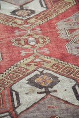 Distressed brick red and gold geometric tribal pattern with latch designs on an Oushak rug.