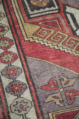 Distressed pile texture with tribal geometric latch designs on a vintage Oushak runner.