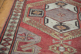 Distressed geometric Oushak runner with tribal latch designs in brick red, grey, and gold.