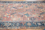 Distressed brick red Heriz carpet with pastel floral motifs and a navy samovar border.