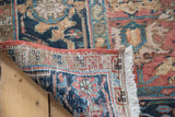 Distressed Heriz carpet showing hand-knotted weave, navy border, and ivory fringe.