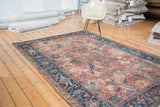Distressed brick red field and navy samovar border with floral design on Heriz carpet.