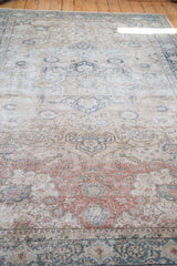 Muted burgundy and ivory scrolling floral arrangements on the distressed pile of a vintage Kaisary carpet.