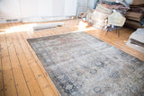 Distressed Turkish Kaisary carpet, faded scalloped medallion, scrolling vines, charcoal, ivory, dusty burgundy.