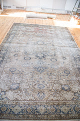 Distressed dark charcoal border and ivory scrolling vine motifs on a vintage Kaisary carpet.