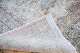 Vintage distressed Kaisary carpet folded, revealing hand-knotted back and faded floral designs.