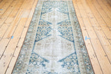 Angled view of distressed Malayer runner, featuring geometric double medallions in ivory, beige, and navy.