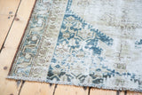 Distressed Malayer runner corner, textured fringe, and faded blue and neutral geometric patterns.