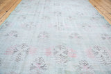 Distressed Oushak carpet with abstract floral lattice in muted green, light red, and charcoal.
