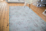 Distressed Oushak carpet with faded abstract florals in muted lime green, light red, charcoal.