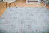 Distressed Oushak rug's abstract light red and charcoal floral motifs on muted lime green.