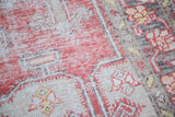 Textured distressed Oushak rug showing faded red, beige, and yellow patterns.