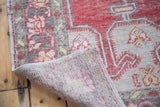 Distressed Oushak carpet's hand-knotted reverse and textured pile in faded cinnabar and beige.