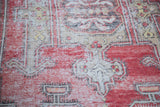 Textured distressed Oushak rug with faded red, ivory, and subtle yellow stylized patterns.