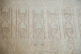Distressed Tulu rug pile showing faded beige, ivory, and subtle celadon interlatched patterns.