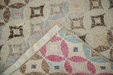 Distressed Oushak rug corner, muted brown patterns revealing vibrant cranberry and blue diamond patterns.