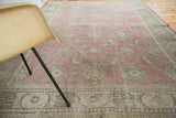 Faded cranberry floral field and abstract grey-green border on a distressed Oushak rug.