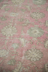 Faded cranberry and grey-green floral motifs on the distressed Oushak rug pile.