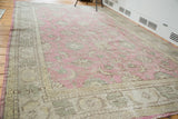 Distressed Oushak rug close-up: faded cranberry red floral field and grey green abstract border.