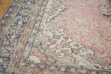 Faded blush rose field with curvilinear ivory and blue medallion on a distressed Oushak rug.