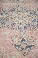 Distressed Oushak rug with faded blush rose field and ornate charcoal motif.