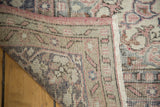 Folded corner of distressed Oushak rug, revealing hand knotted back and faded blush selvedge.