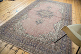 Distressed Oushak carpet's corner showing muted blue, brown border, and soft fringe.