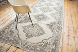 Textured distressed Oushak runner showing muted brown medallion and intricate border.
