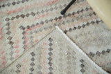 Distressed vintage Oushak rug showing its modern checkered pattern and hand-knotted foundation.