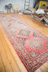 Geometric border details on distressed Oushak runner in faded cinnabar, charcoal, ivory tones.
