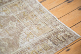 Textured pile and worn fringe of a distressed Oushak rug in neutral beige and faded celadon.