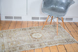 Distressed Oushak rug featuring faded medallion, geometric borders, and visible aged texture.