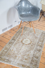 Faded beige and celadon green distressed Oushak rug with geometric border and tendrils.
