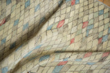 Textured pile of a distressed Oushak runner showing geometric diamonds with varied color fills.