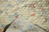 Distressed Oushak runner folded, showing textural pile, ivory, blue, red diamond motif, and fringe.