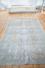 Textured pile of distressed Oushak carpet with softened ivory, silver, and peach tones.