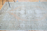 Vintage distressed Oushak carpet with faded peach, ivory, and silver tones highlighting abrashes.